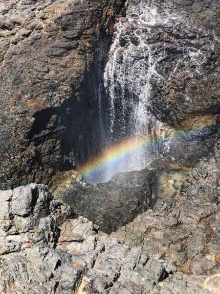 rainbow reflection on water flowing over rock